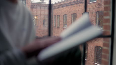 person enjoys reading by the window on a snowy day