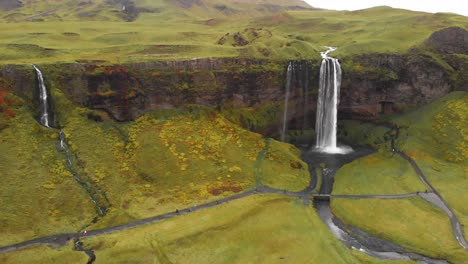 Hiking-trail-below-rock-cliff-with-Seljalandsfoss-in-nordic-Iceland
