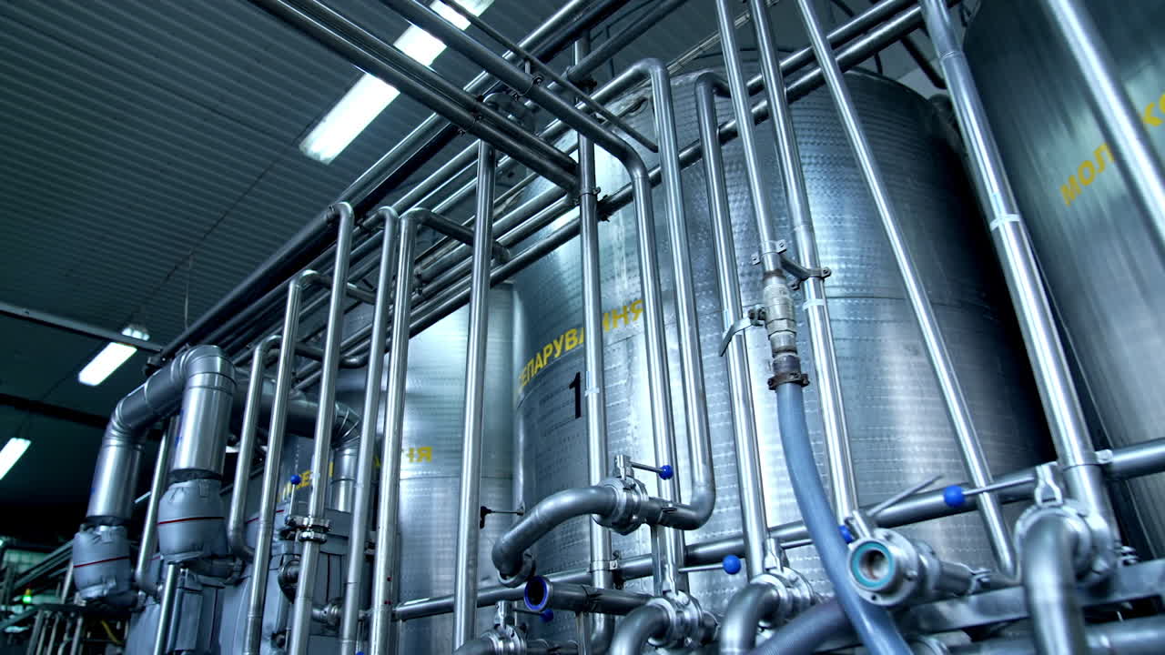 Metal pipelines joined together into a very complicated system. Gradual distancing from a huge reservoir for milk at diary plant.