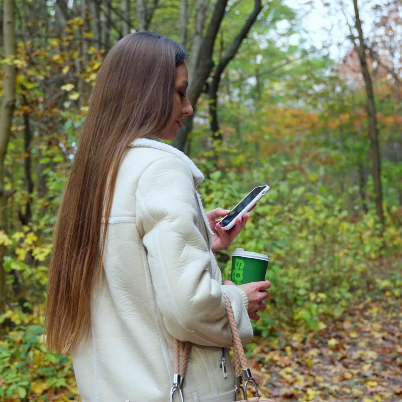 Cute woman with new technology phone outdoor in forest. Lady speaks on the phone in autumn park