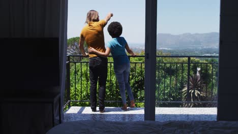 rear view of mixed race couple enjoying the view while standing in the balcony at home