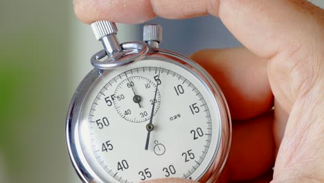 the man presses the start button of a vintage stopwatch he is holding.