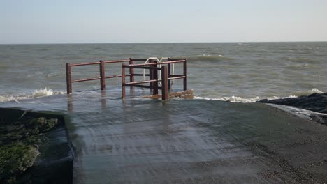 Portmarnock-Beach,-Fingal,-Dublin,-Ireland---Waves-Splashing-and-Crashing-Against-the-Pier---Zoom-In-Shot