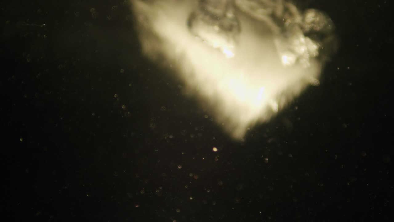 Ice cube falling in water in slow motion.