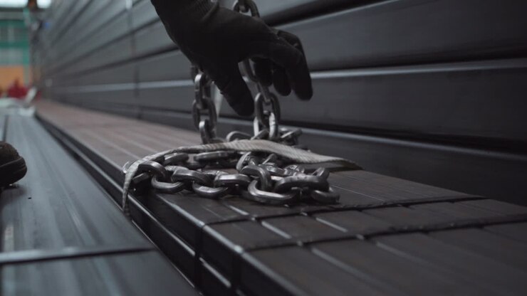 Industrial worker attaching steel chain to lift heavy construction materials