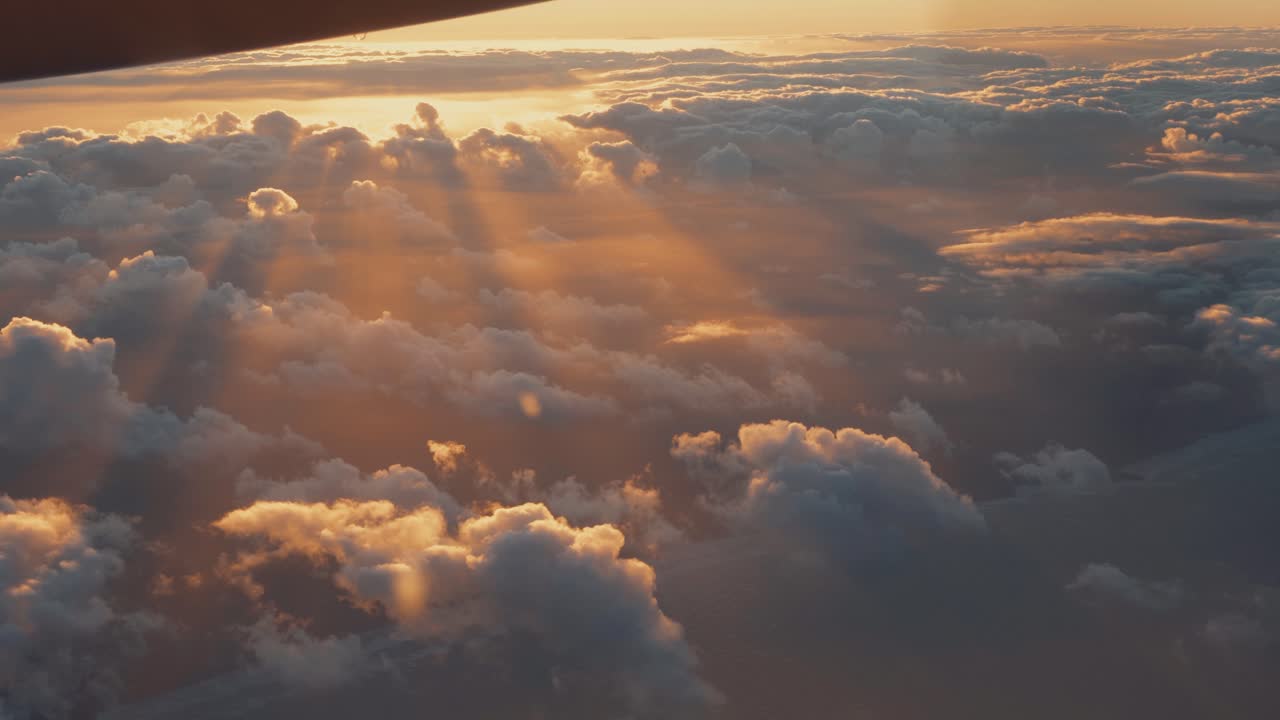vista aérea desde la ventana del avión de nubes blancas en el cielo dorado