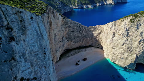 Navagio-Beach,-Shipwreck-Beach,-or-Smugglers-Cove-is-an-exposed-cove-on-the-coast-of-Zakynthos,-in-the-Ionian-Islands-of-Greece---aerial