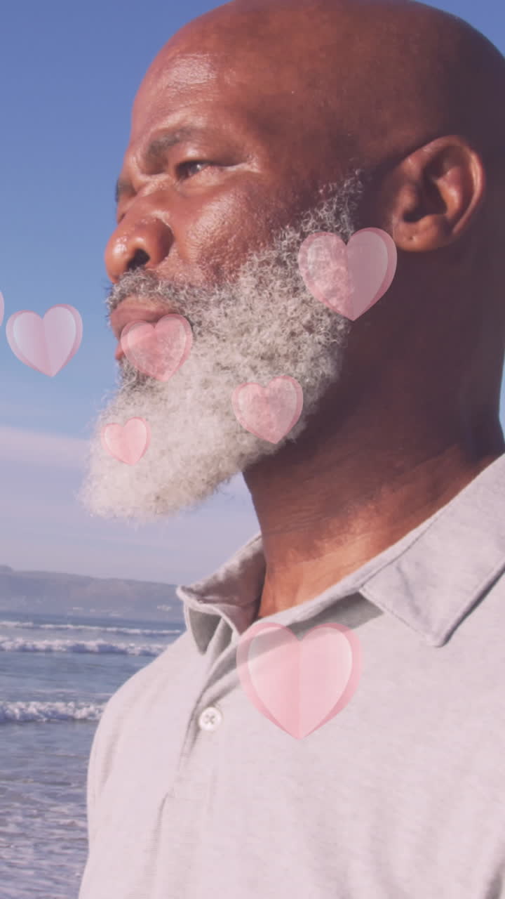Animation of hearts over senior african american man at beach