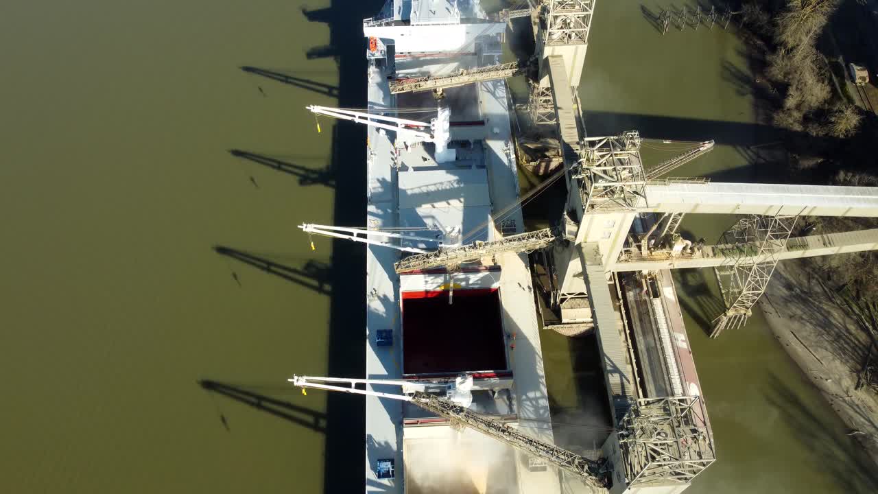 US, Oregon, Portland, 2026-02-15 - Drone view of grain being loaded from storage silos onto a bulk carrier ship on the Wilamette River at the Port of Portland Terminal 5, in Winter