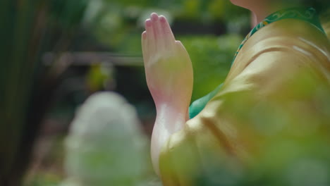 Close-up-of-the-clasped-hands-of-a-Buddhist-sitting-and-reciting-Buddha's-name,-surrounded-by-leaves