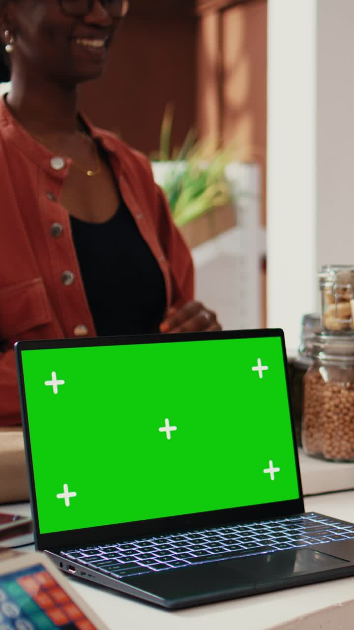 Commerciante di video verticali che vende prodotti ecologici vicino a un laptop con greenscreen