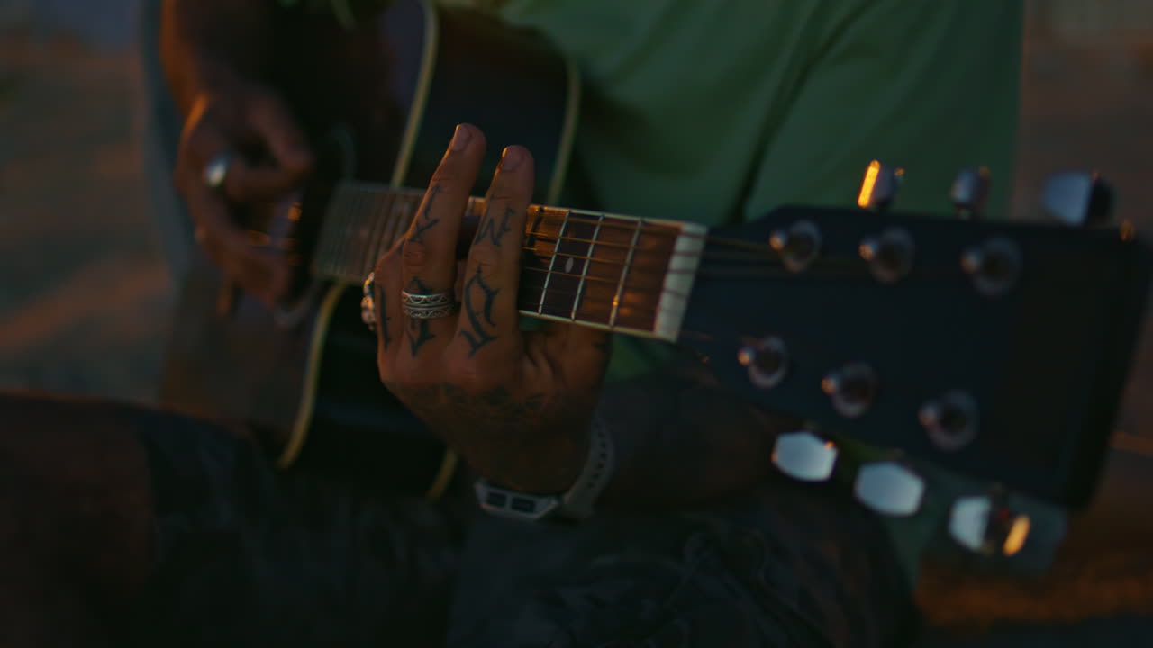 Musikers fingre spiller guitar om natten tæt på. Guitaristens hænder rører ved strengene