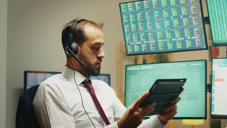 stock market broker having a conversation on headphones while using tablet computer