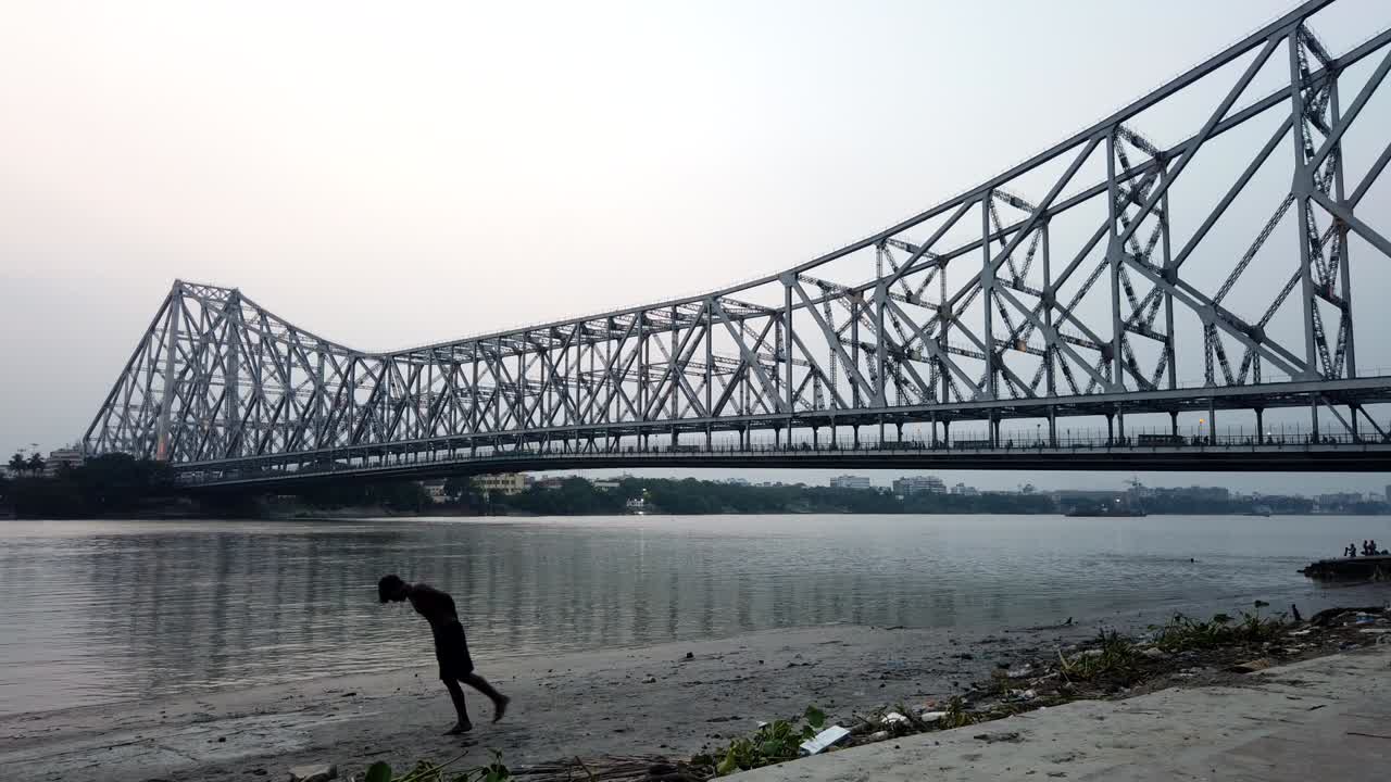 Kolkata : Timelapse of Howrah bridge along with children playing in the ghats in the foreground.