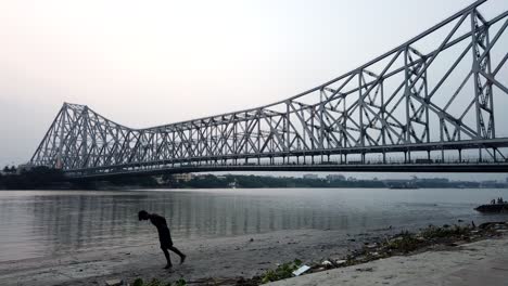 kolkata : timelapse of howrah bridge along with children playing in the ghats in the foreground.