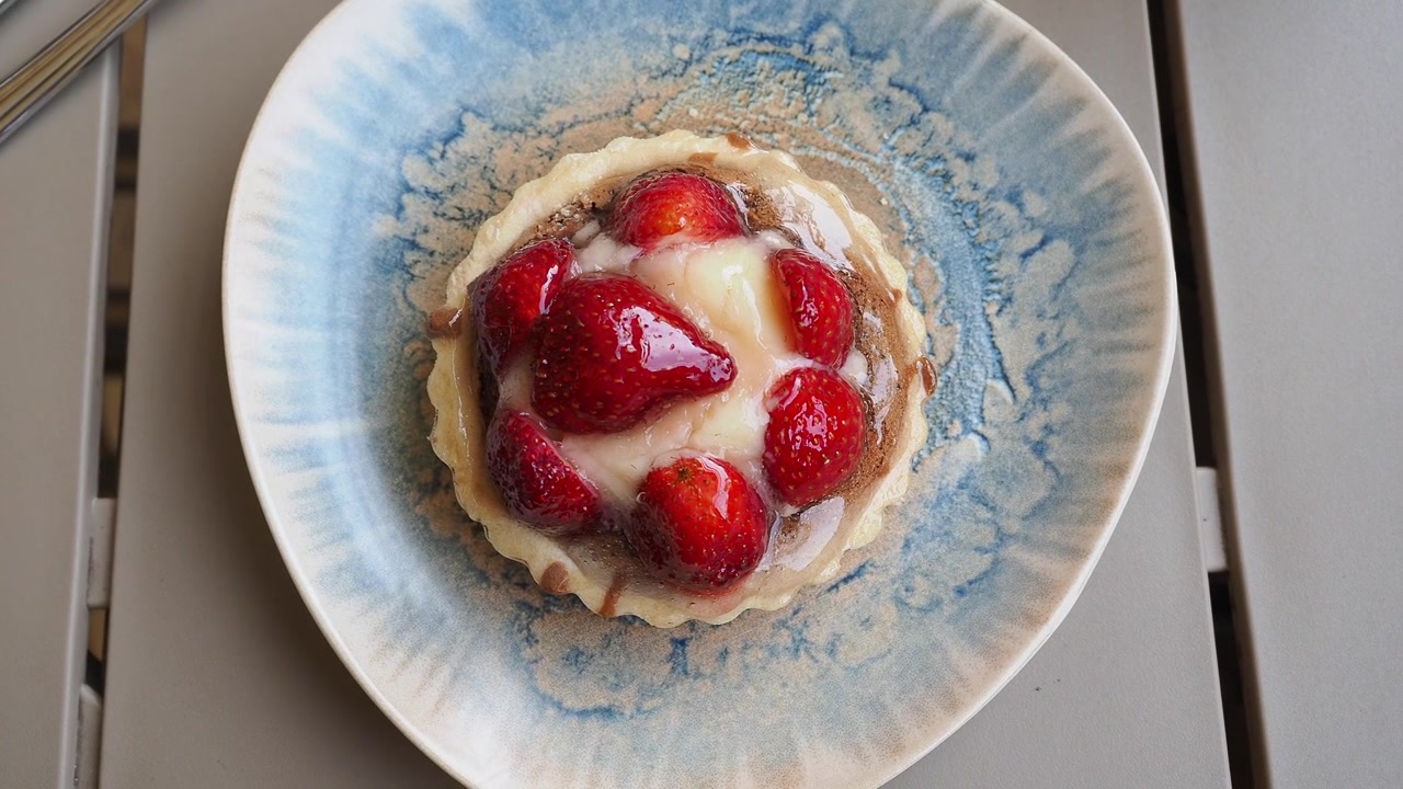 Crostatina individuale alle fragole con panna e frutti di bosco freschi.