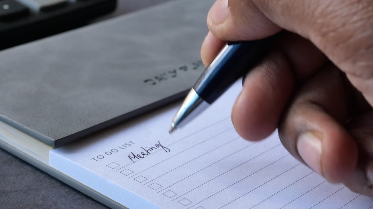 Person writing a to-do list for a meeting