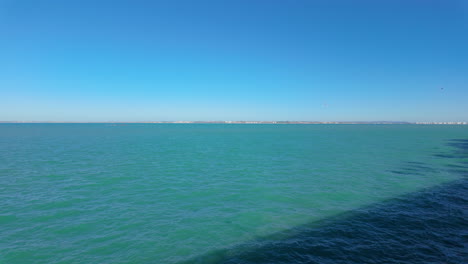 the expansive bay of cádiz viewed from a seaside walkway, featuring tranquil turquoise waters meeting the clear blue sky at the horizon