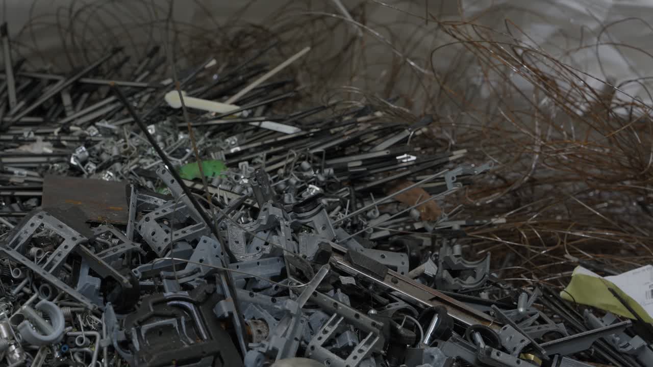 Großer Haufen aus gemischtem Metallschrott, Halterungskomponenten und verwickeltem Draht, gesammelt zur Recyclingverarbeitung.
