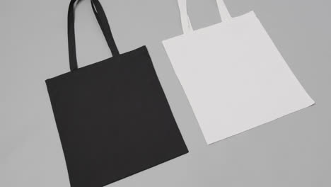 Close-up-of-white-and-black-bags-on-grey-background,-with-copy-space,-slow-motion