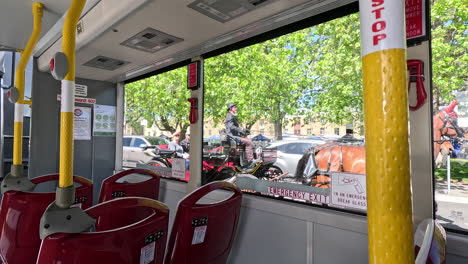 sitting on a bus, a horse and cart leisurely trot by, creating a serene moment in a peaceful town. the bright day enhances this charming sight.