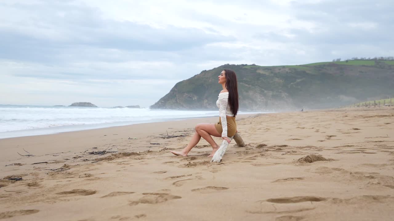 Woman Sitting on Driftwood at the Beach