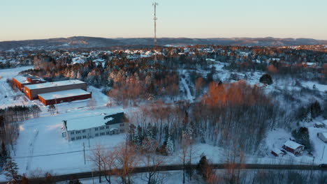 pintoresco vuelo aéreo de invierno hacia una torre de sitio celular en un vecindario cubierto de nieve