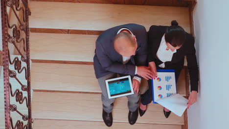 Top-view-of-businessman-holding-tablet-analysing-graphs