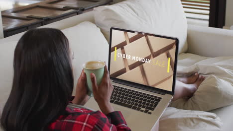 una mujer biracial usando una computadora portátil en casa comprando en línea en el día de venta del lunes cibernético, en cámara lenta