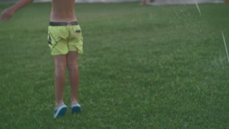 Child-getting-shower-with-automatic-garden-sprinkler