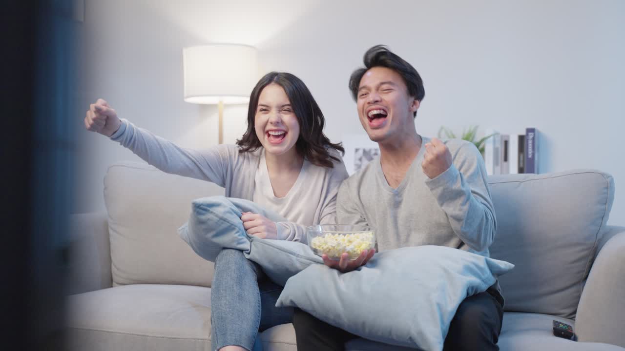 tv 를 보고 팝콘 을 먹고 있는 부부