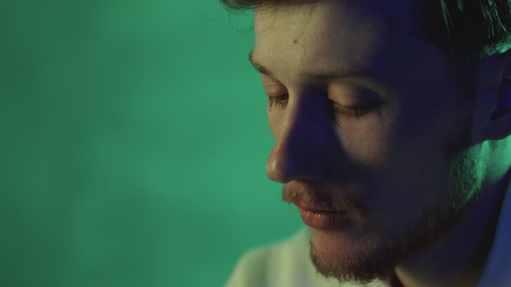Ritratto di un giovane uomo su uno sfondo colorato con luci al neon. Primo piano.