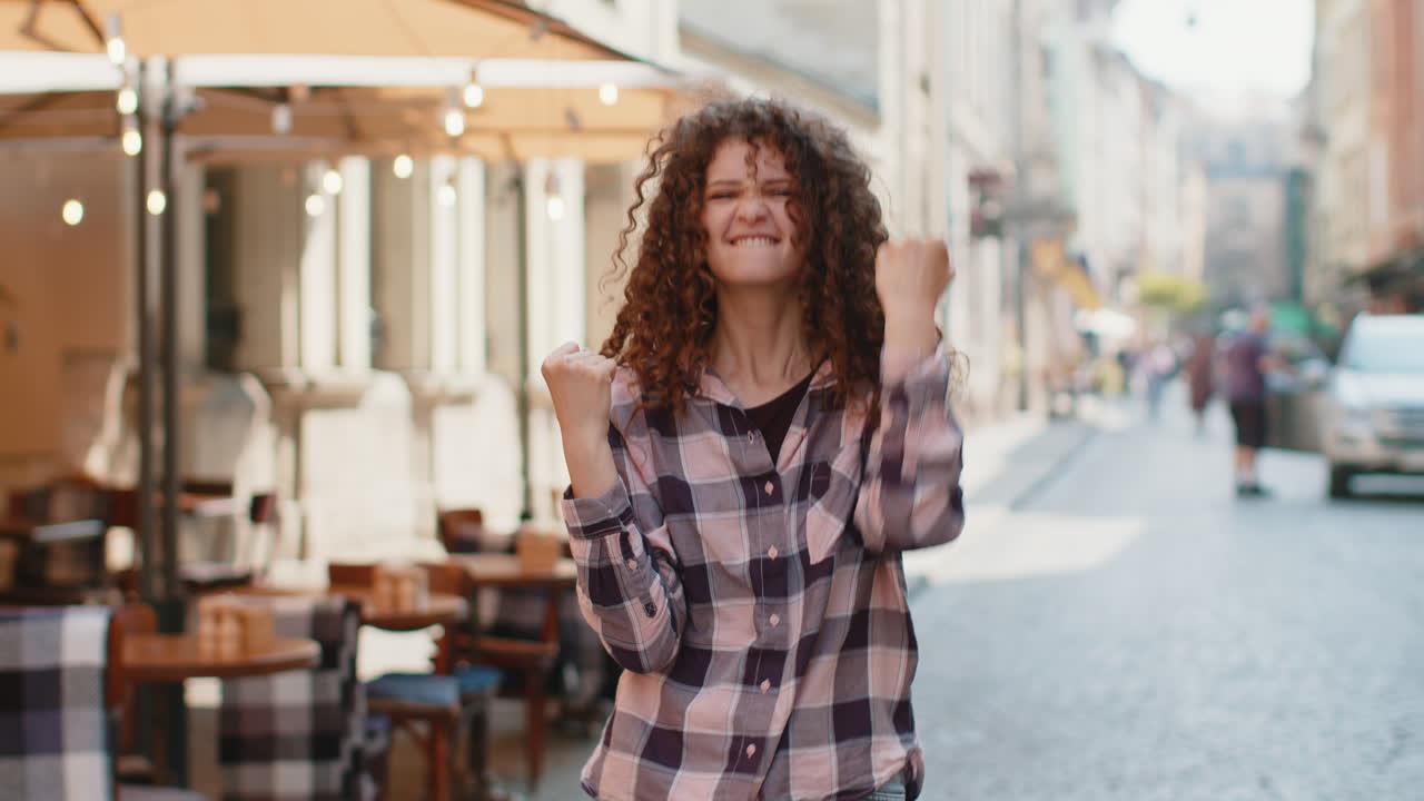 Young woman shouting celebrating success winning goal achievement good victory news in city street