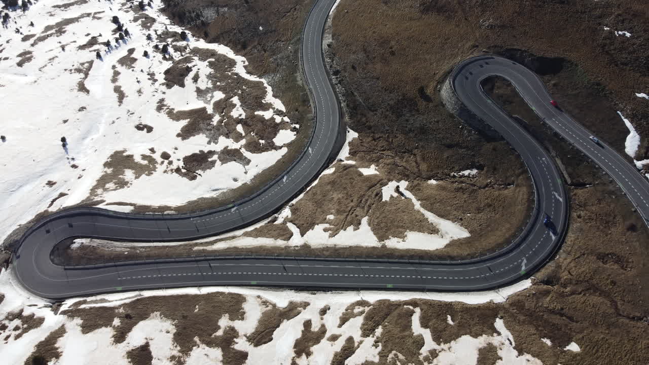 una carretera asfaltada negra única con giros y vueltas a través de una escena nevada