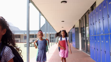 walking in school hallway, two girls with backpacks heading to class