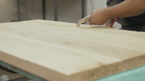 carpentry uses air compressor blowing off sawdust oak tabletop