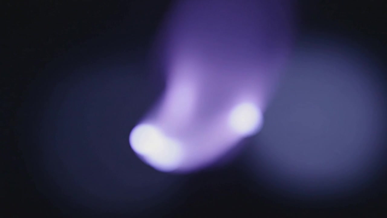 Registrazione di una singola luce viola che si allunga verso il basso in uno studio buio, con un disco bokeh.