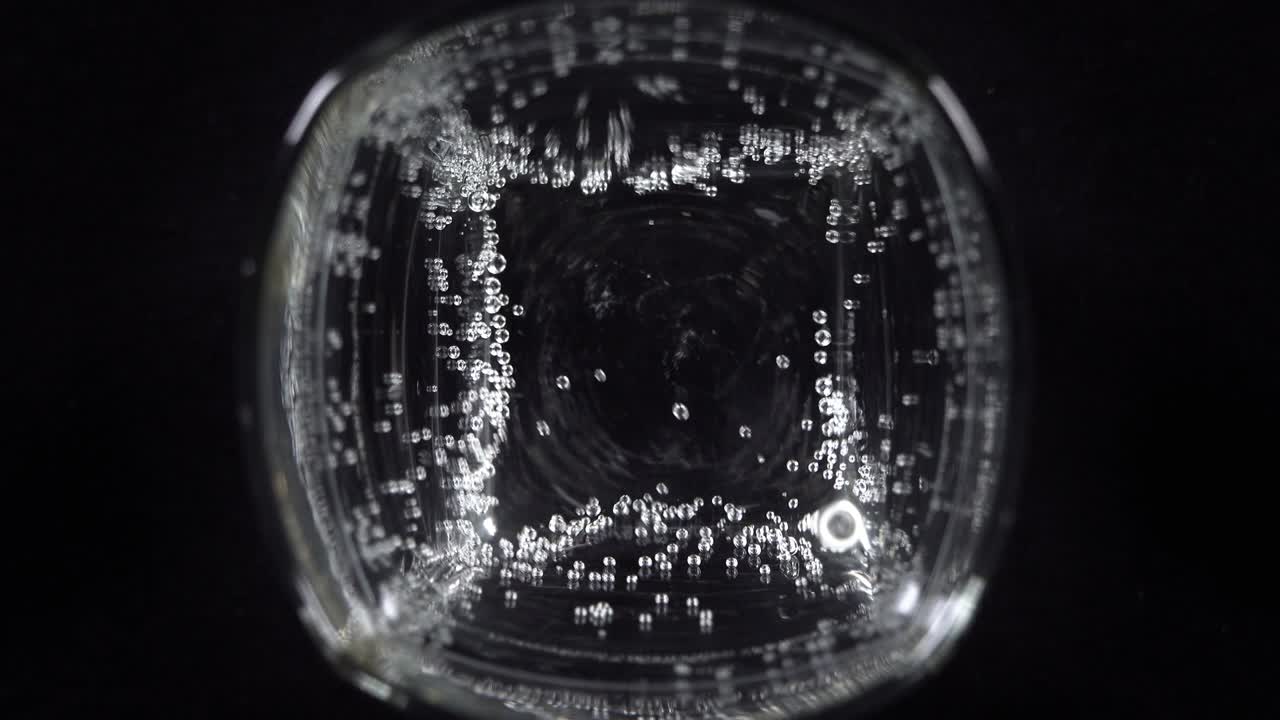 유리잔에 미네랄 워터 거품의 근접. 어두운 배경에 산소 공을 가진 탄산 신선한 스파클링 음료의 매크로 상점