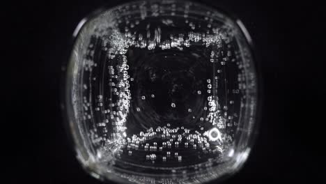 close up of mineral water bubbles in the glass. macro shop of carbonated fresh sparkling drink with oxygen balls on dark background