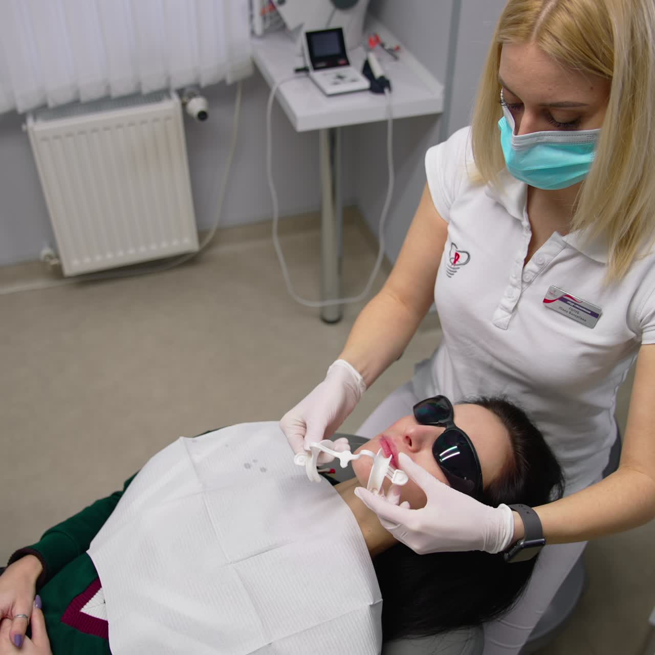 Giovane donna sulla poltrona del dentista. La dentista estrae uno strumento di plastica dalla bocca del paziente. Vista dall'alto.