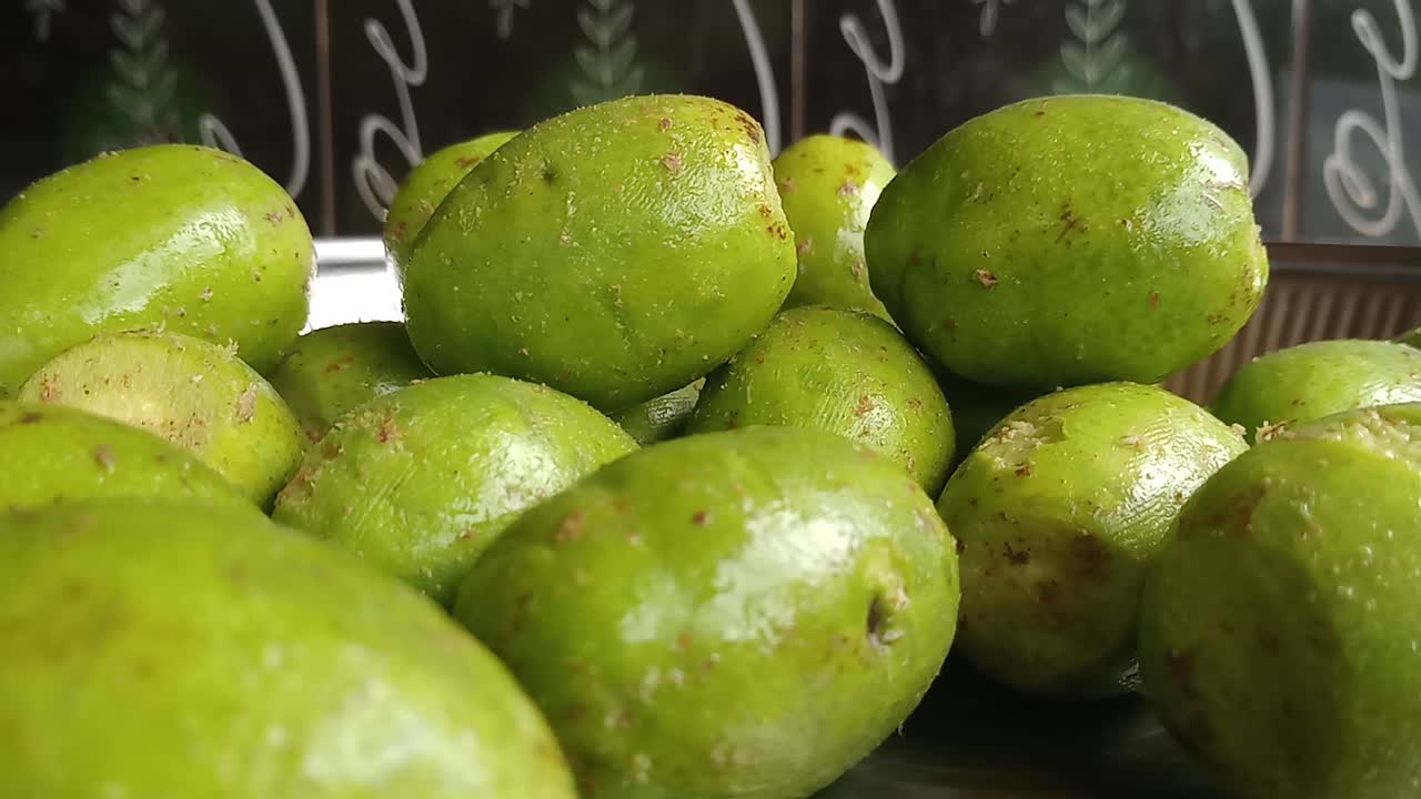 Close up zoom in shot of green Hog Plum in fruit bowl on table