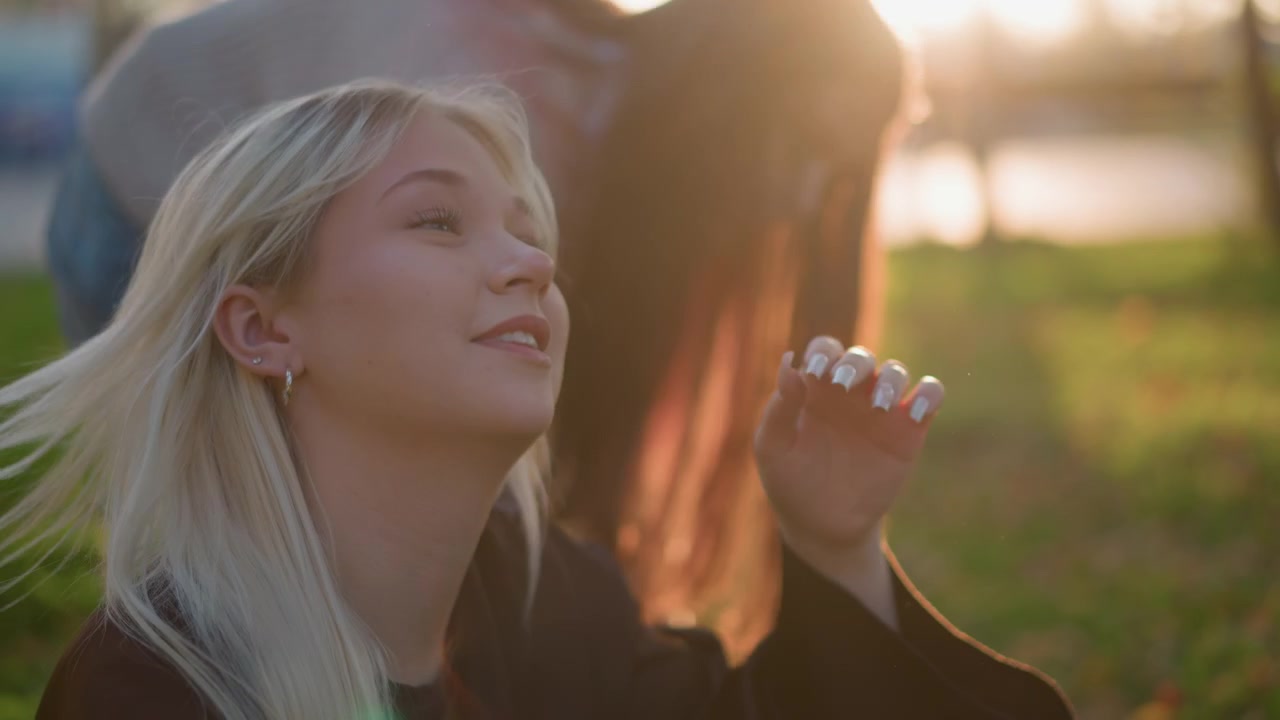 Giovane donna bionda che si rilassa al parco al tramonto