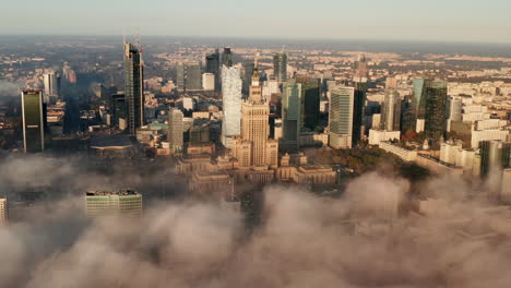 Aerial-panoramic-footage-of-downtown-high-rise-buildings-in-morning-sun.-Historic-PKIN-buildings-and-modern-office-skyscrapers-above-fog.-Warsaw,-Poland