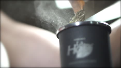 the meticulous process of mate preparation, delicately pouring yerba mate leaves into a mate gourd, exemplifying the care and tradition behind this south american ritual