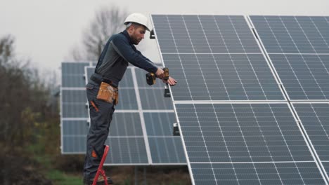 a professional man in a special uniform installs a solar panel at a solar power plant