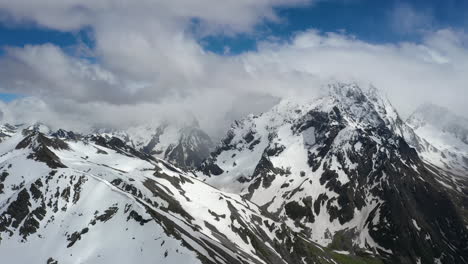 vuelo aéreo a través de nubes montañosas sobre hermosos picos nevados de montañas y glaciares.