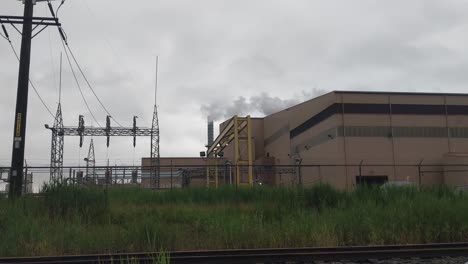 steam rising from a steel plant, gray skies, brick building, railroad tracks