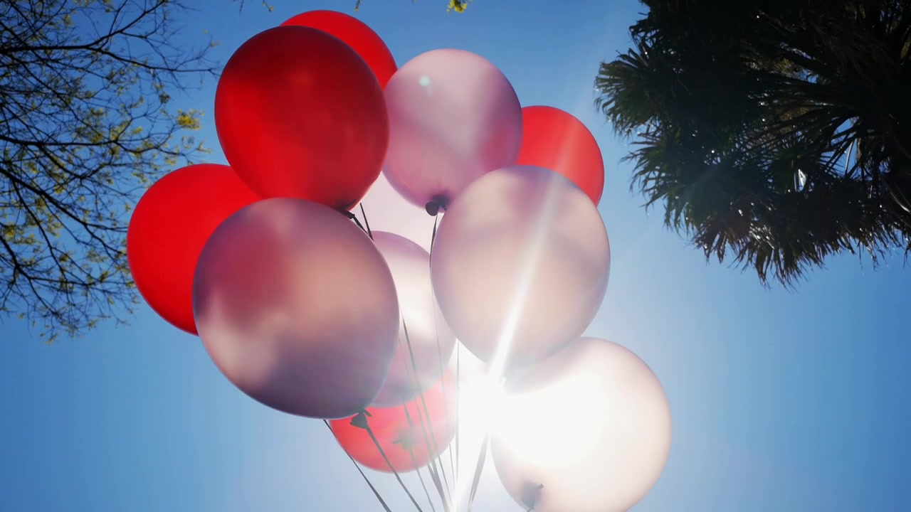 Palloncini trasparenti che girano davanti al sole e al cielo, ondeggiando al vento