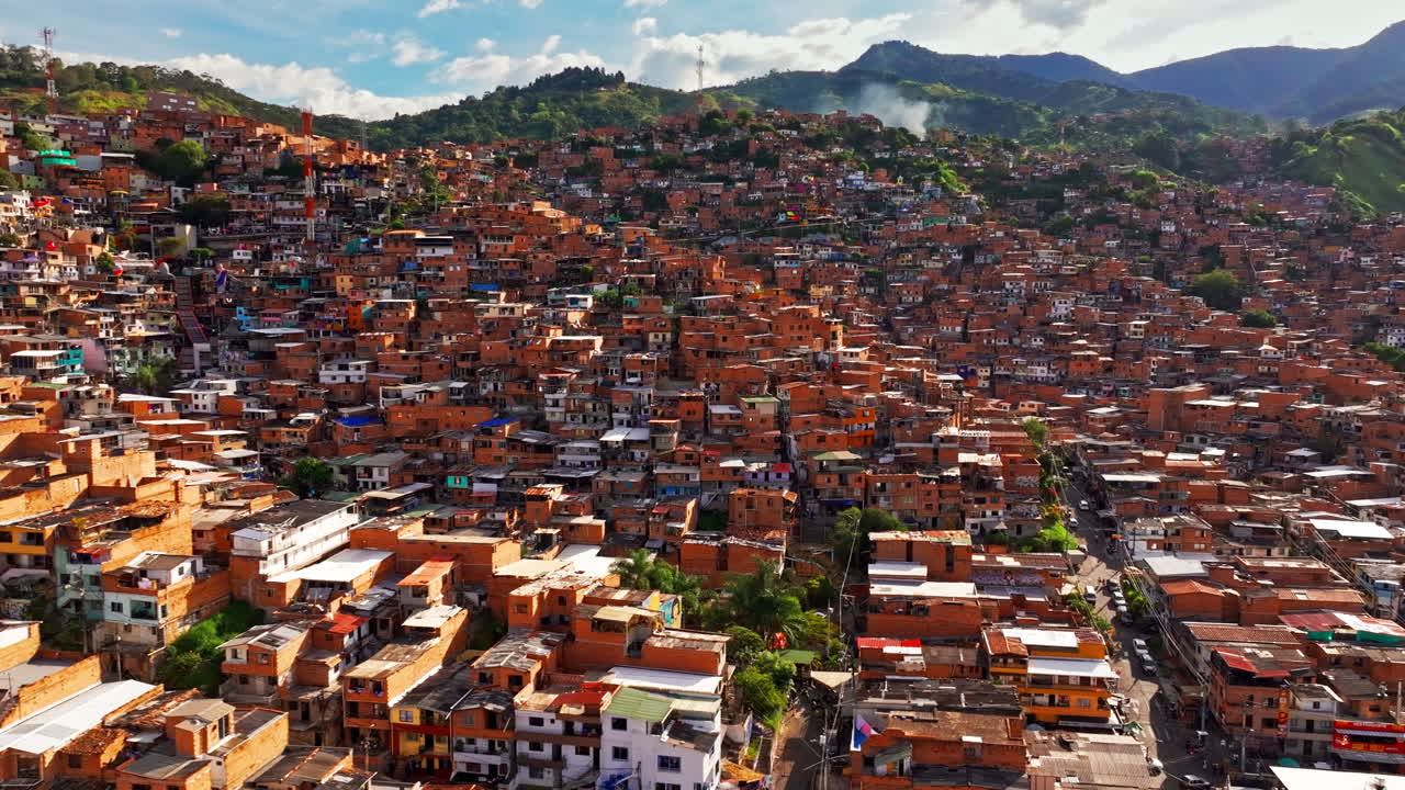 Clip da drone aereo di Medellin con un'ampia distesa urbana, densità urbana e quartieri a strati sotto le montagne circostanti.