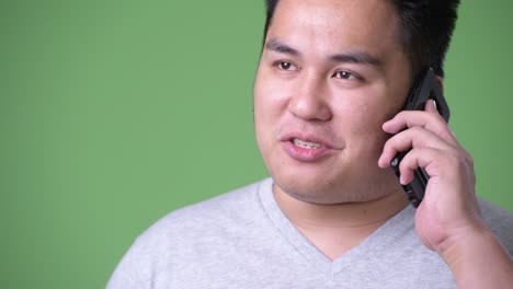 young handsome overweight asian man against green background